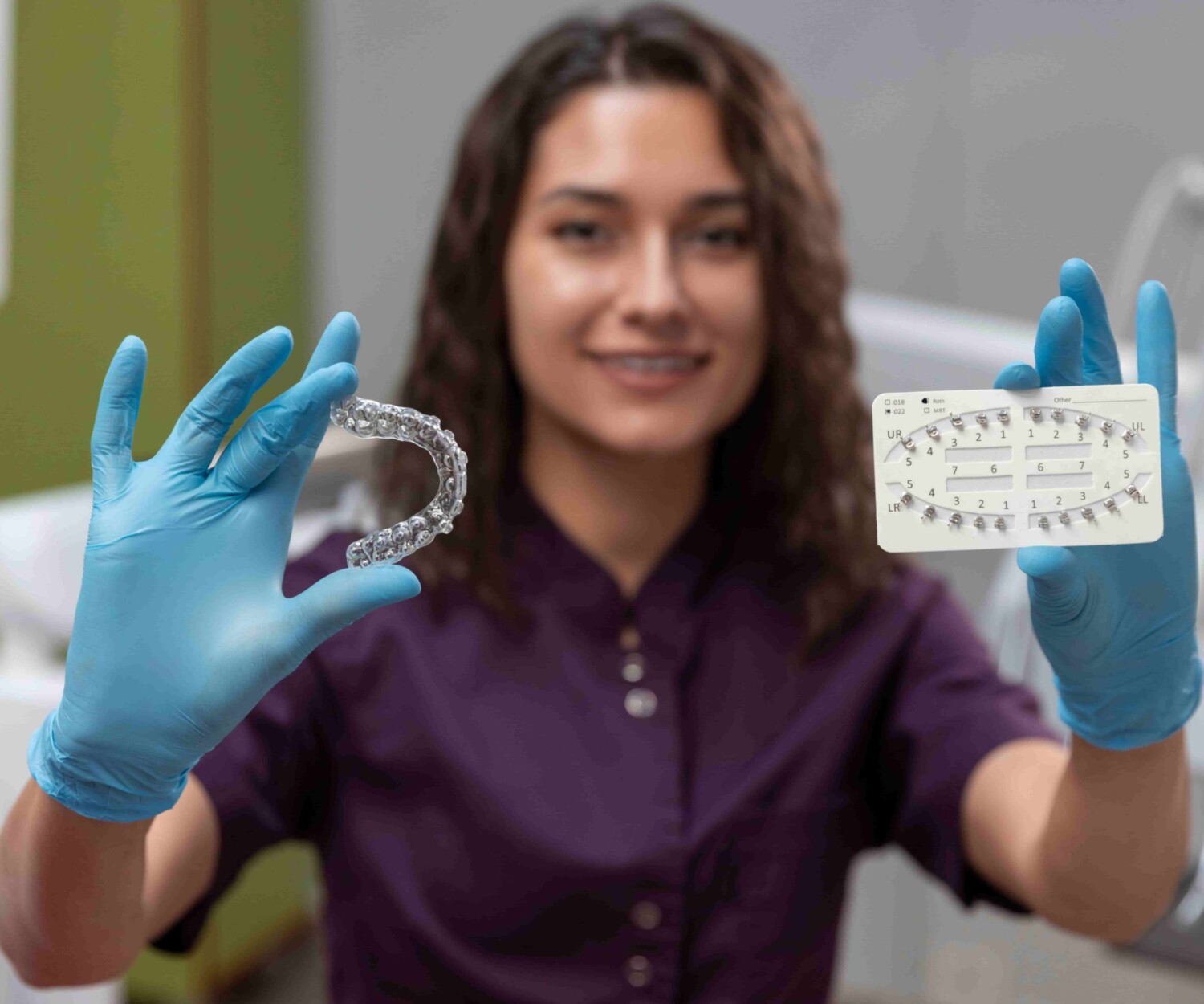 Dentist holding up aligners and braces