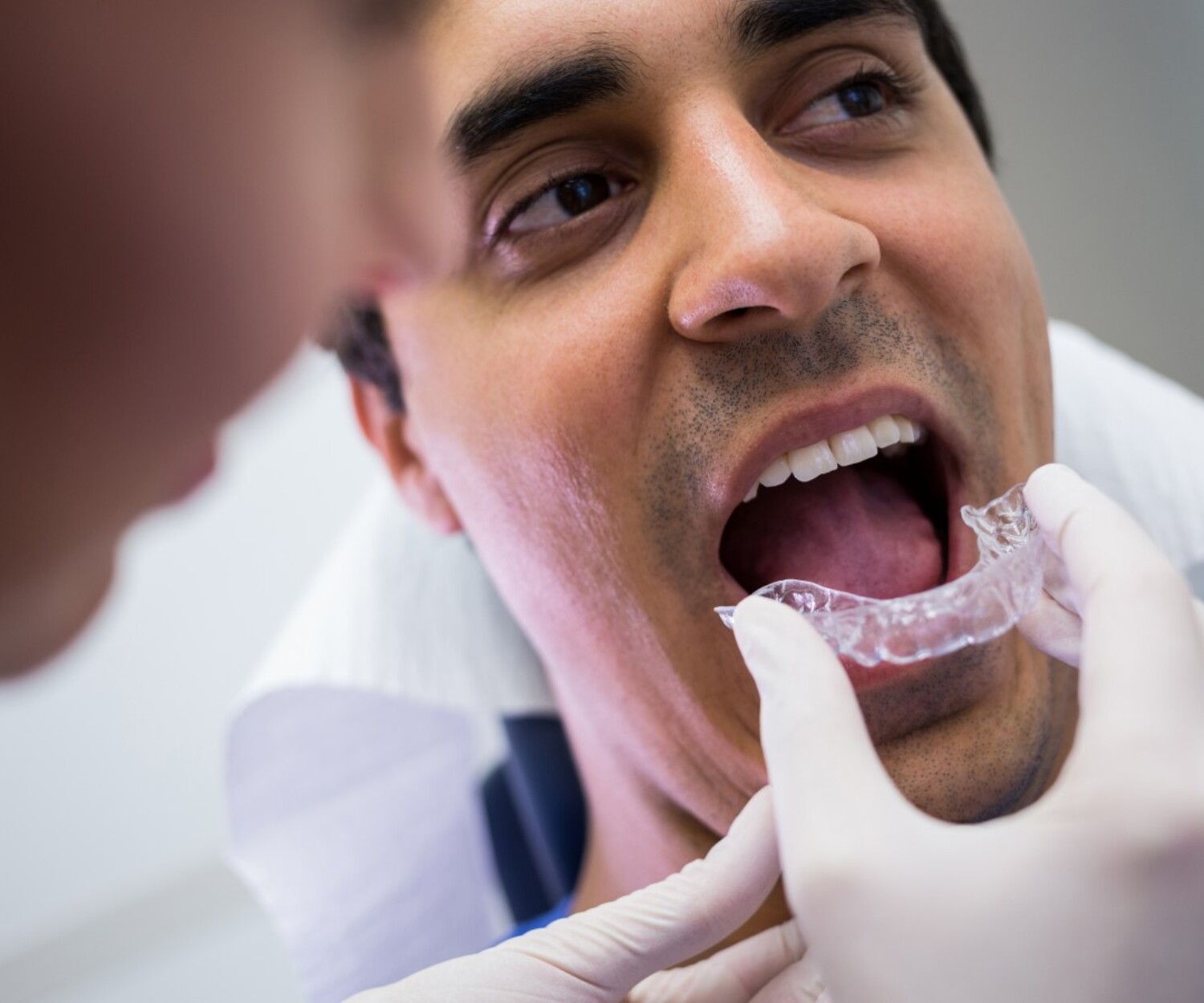 Banner image of dentist assisting patient wear invisible braces
