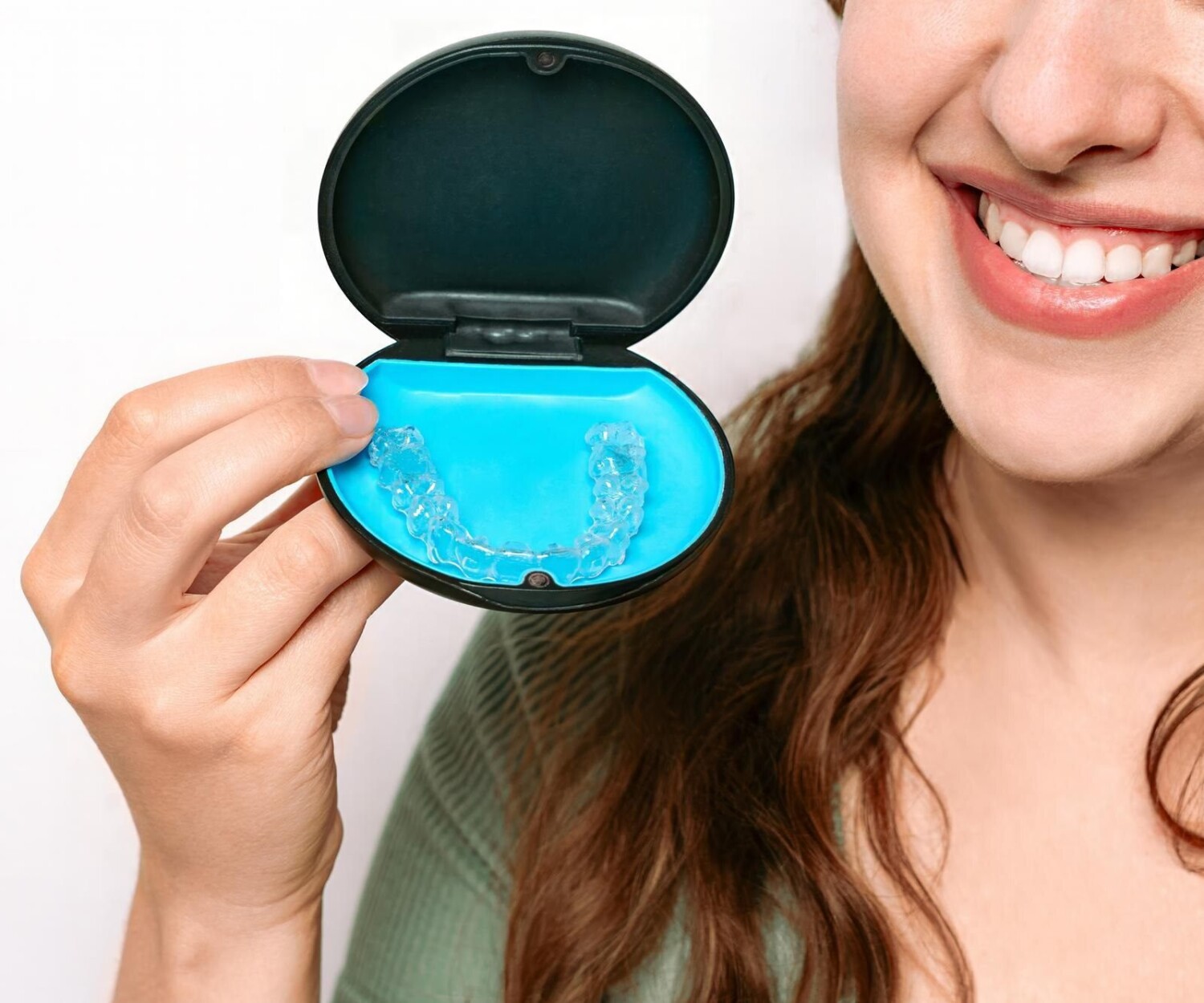 Close-up of a happy woman presenting a dental whitening tray with her bright teeth visible.