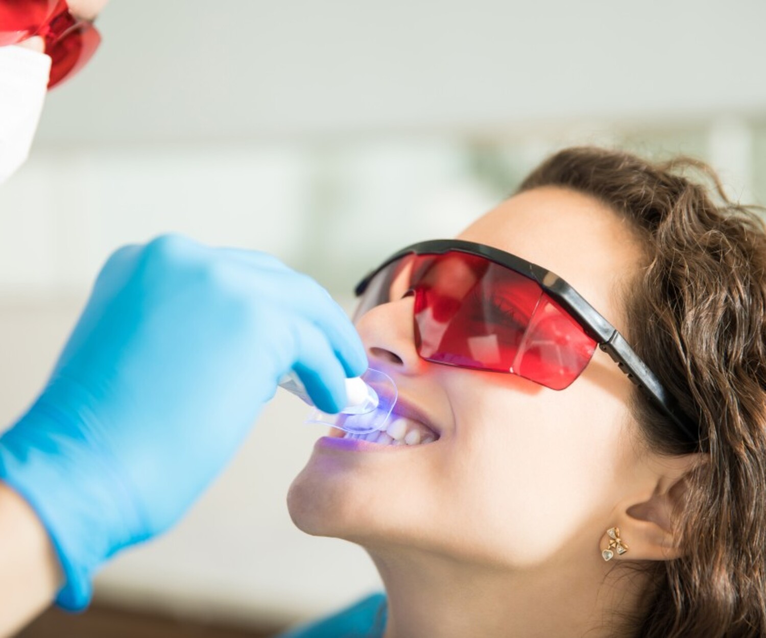 Banner image of closeup young woman having her teeth whitened with ultraviolet light dental clinic