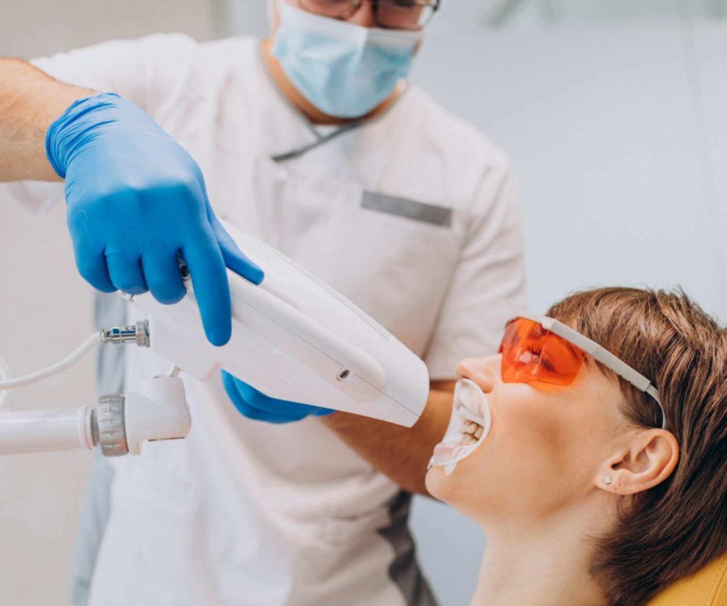 woman whitening teeth dentistry with special equipment