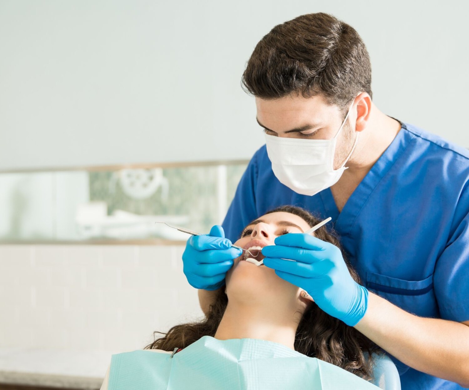 Male dentist examining young woman with dental carver at medical clinic